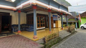 A building with a covered entrance, a blue sofa outside, and a flag. - OYO Homes 91134 Desa Wisata Tebing Lingga (Nglebo)
