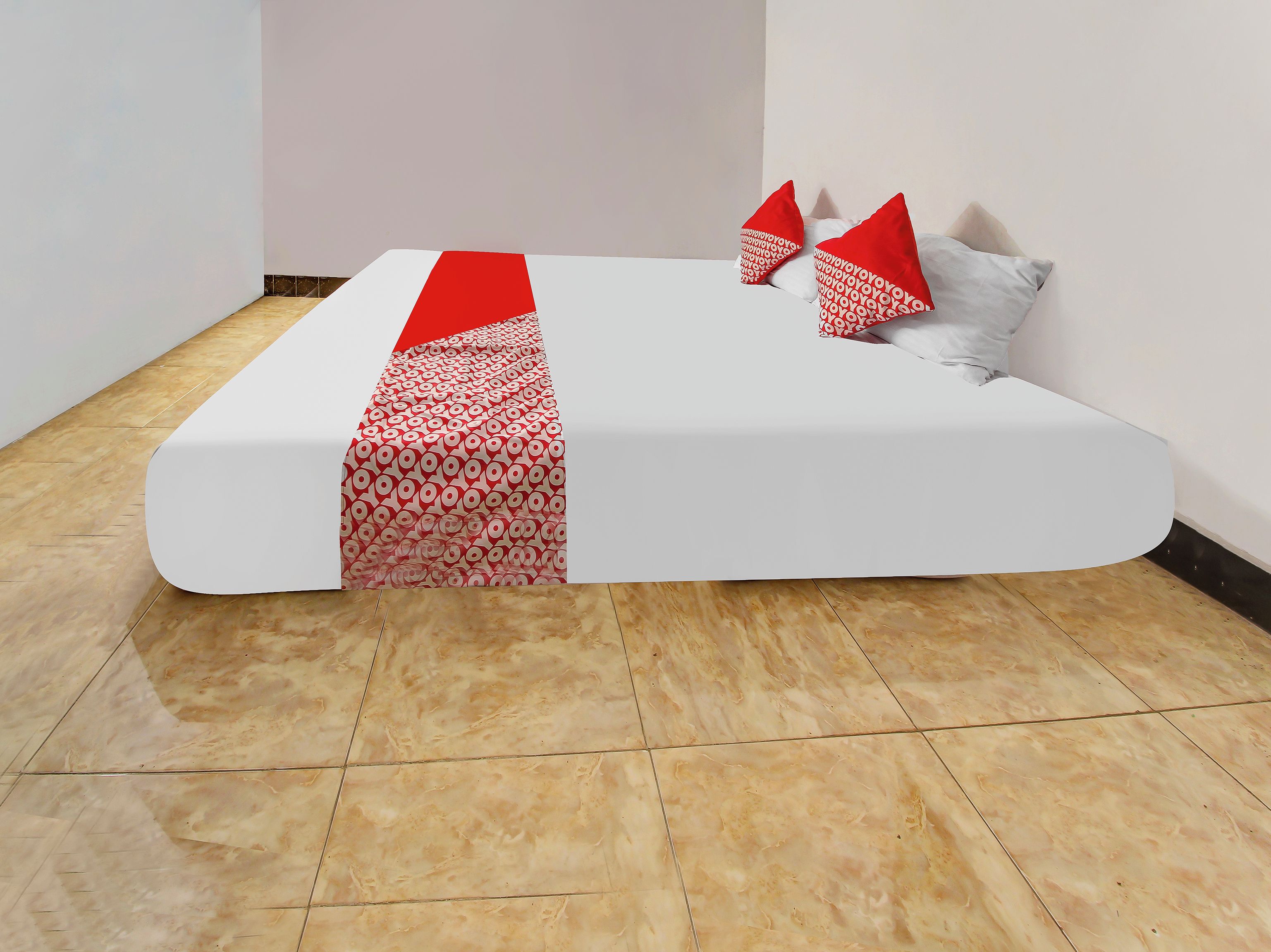 A neatly made bed with a white mattress and red patterned bedspread.