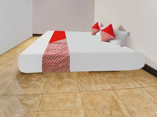 A neatly made bed with a white mattress and red patterned bedspread.