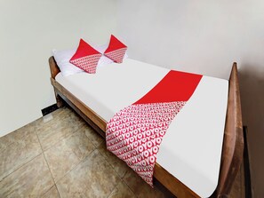 A small bed with a white mattress and red and white patterned bedspread.