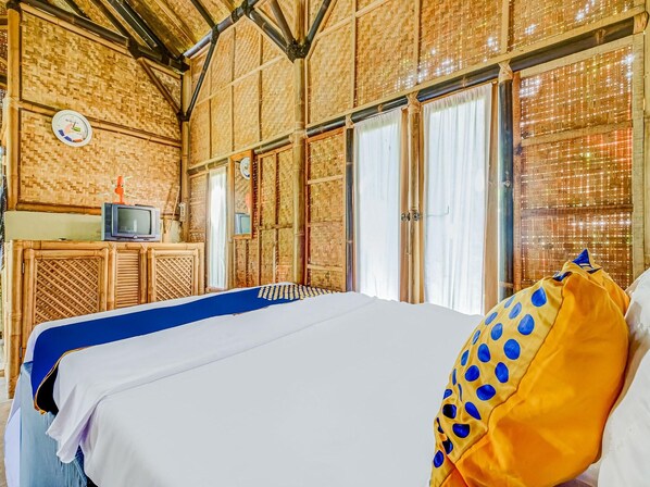 Una habitación con una cama, televisión y un reloj en la pared.