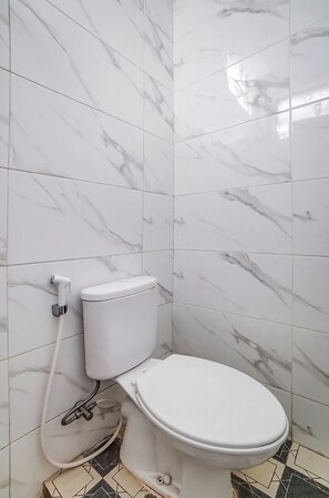 Une salle de bain avec des toilettes, des carreaux de marbre blanc et un sol à motifs.