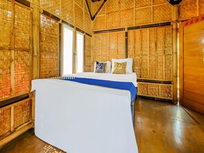 Ein Zimmer mit einem großen Bett, Holzwänden und einem Fenster.