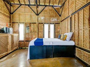 Ein Zimmer mit einem Bett, einem Fernseher auf einer Holzkommode und einer Wand aus gewebtem Bambus.