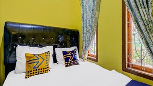A bed with white bedding and two decorative pillows with geometric patterns.