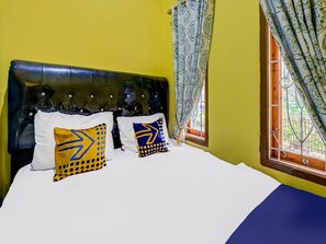Una cama con ropa blanca y dos almohadas decorativas de diseños geométricos.
