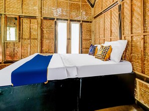 A bed with a white mattress and blue blanket, two pillows with geometric patterns, and a woven wall design. - OYO Homes 91067 Desa Wisata Santanamekar (Cisayong)