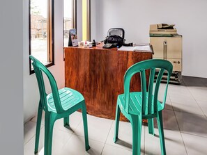 A workspace with a wooden desk, two green chairs, a black office chair, a Canon printer, and a calendar on the wall. - OYO Homes 91067 Desa Wisata Santanamekar (Cisayong)
