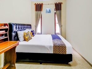 A neatly made bed with a patterned bedspread, a black upholstered headboard, and two pillows. - OYO Homes 91067 Desa Wisata Santanamekar (Cisayong)