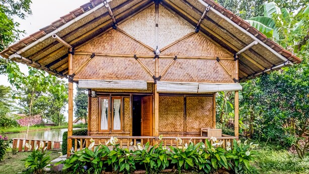A bamboo house with a porch, surrounded by lush greenery. - OYO Homes 91067 Desa Wisata Santanamekar (Cisayong)
