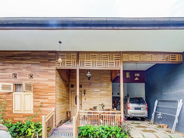 Ein Holzhaus mit überdachter Veranda, ein Auto auf dem Grundstück und eine an der Wand angelehnte Leiter.