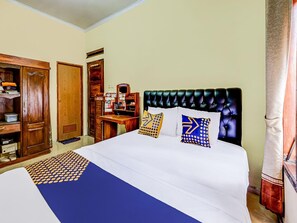 Una habitación de hotel con una cama, un armario de madera, un escritorio con espejo y una ventana con cortinas.
