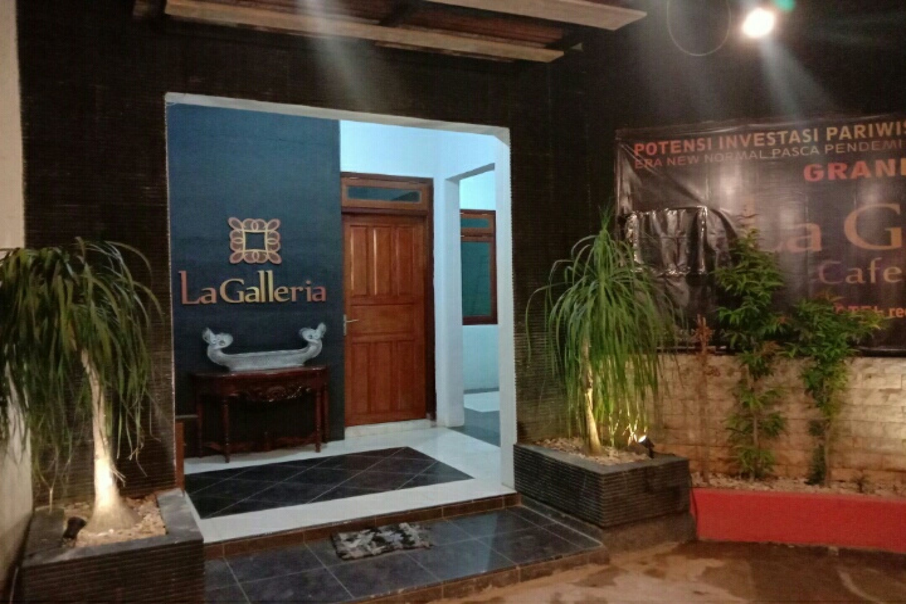 L’entrée d’un hôtel, avec une enseigne indiquant « La Galleria » et une banderole annonçant « Grand Café ».