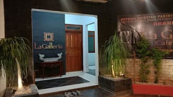 Entrada de um hotel com um letreiro 'LaGalleria' e um banner para 'Grand Cafe'.