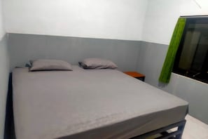 A single bed with a grey mattress and two pillows in a room with light blue walls. - OYO 91179 Hotel Lagalleria (Sumenep)