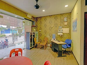 A reception area with a counter, chairs, a water dispenser, and a refrigerator. - Spot ON 91267 Sar Inn (Batam)