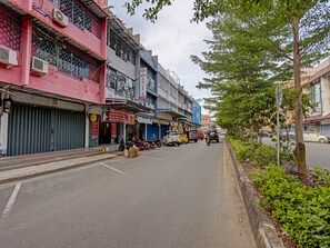 Una calle con comercios cerrados, una acera arbolada y motocicletas estacionadas.