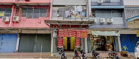Un edificio de varios pisos con unidades de aire acondicionado, un local comercial con un letrero y motocicletas estacionadas frente.