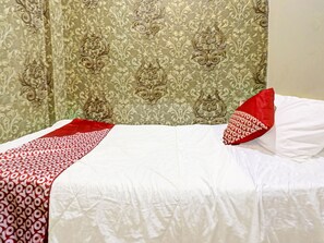 A neatly made bed with a white and red bedspread, a red pillow, and a green patterned curtain in the background. - Spot ON 91267 Sar Inn (Batam)