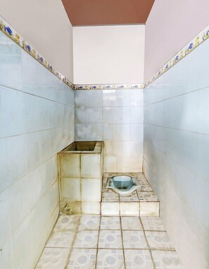 A small, tiled bathroom with a toilet and a sink.