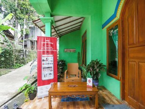 A green building with a wooden table and chairs outside, a banner, and a door.