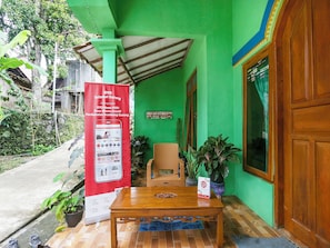 Un bâtiment écologique avec une table et des chaises en bois à l’extérieur, une banderole et une porte.