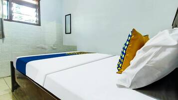 A bed with white and blue bedding, a wooden headboard, a window with a view, and a white wall.