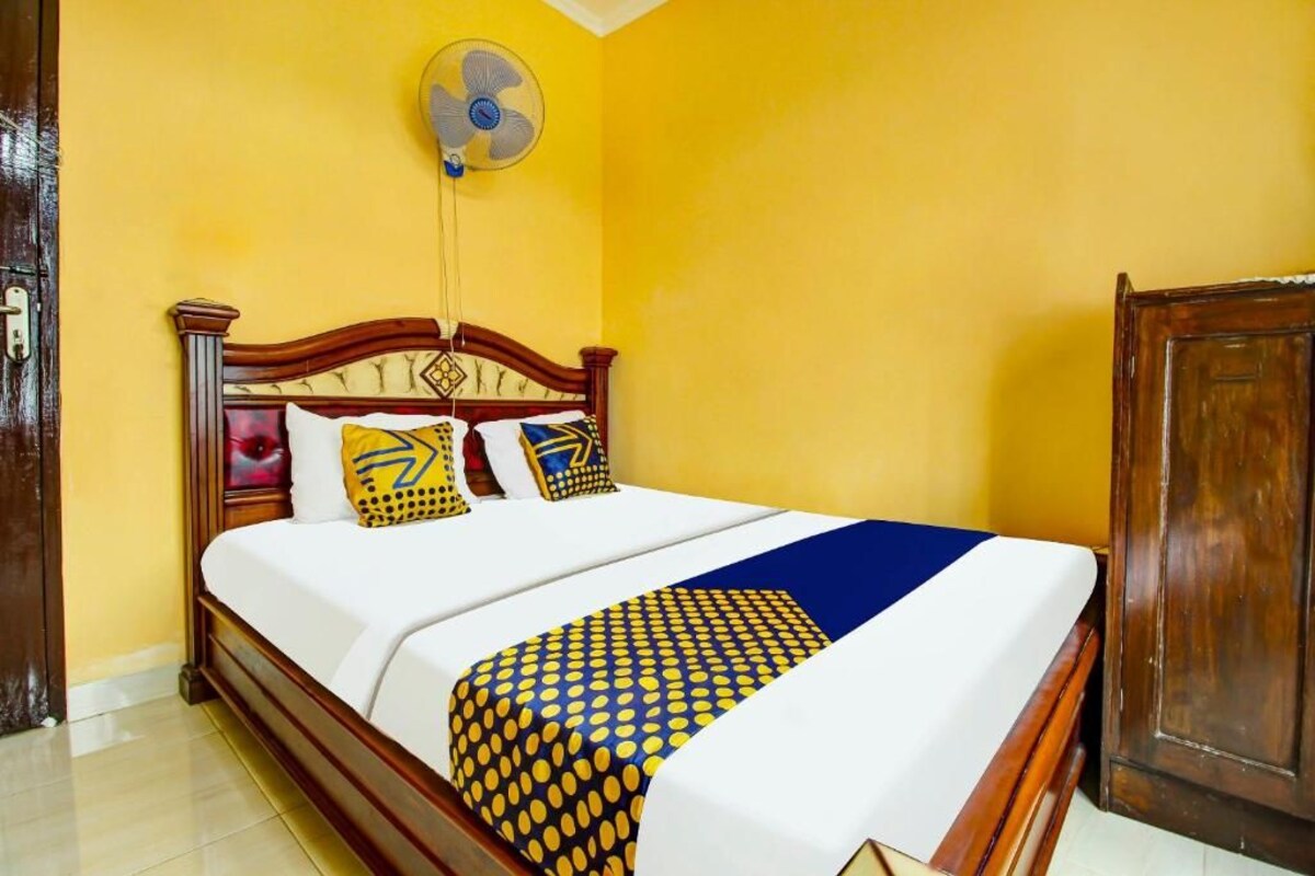 A bed with a wooden headboard, a white mattress, and patterned bedspread.