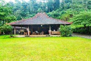 A traditional building with a tiled roof, surrounded by lush greenery and a grassy area. - OYO 91242 Desa Wisata Cibuntu Kuningan Syariah (Mandirancan)