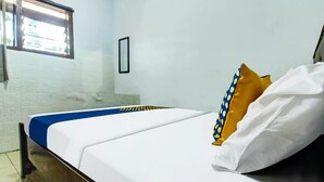 Ein Bett mit weißer und blauer Bettwäsche, ein Holz-Kopfteil, ein Fenster mit Aussicht und eine weiße Wand.