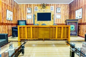 A reception area with a wooden desk, chairs, a television, and framed certificates on the wall. - OYO 91242 Desa Wisata Cibuntu Kuningan Syariah (Mandirancan)