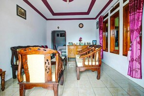 A dining area with wooden furniture, a piano, and a window with curtains. - OYO 91242 Desa Wisata Cibuntu Kuningan Syariah (Mandirancan)