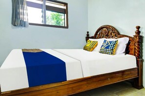 A bed with a blue and white bedspread, two patterned pillows, and a wooden headboard. - OYO 91242 Desa Wisata Cibuntu Kuningan Syariah (Mandirancan)