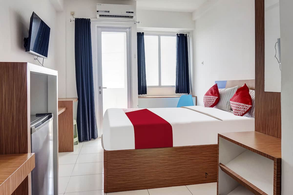 Habitación de hotel con cama, televisor, escritorio y ventana con cortinas.