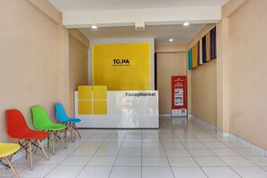 Un espace d’accueil avec une enseigne « TO.HA », un comptoir de réception et des chaises colorées.