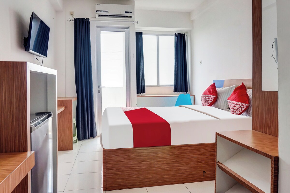Une chambre d’hôtel avec un lit, une télévision, un bureau et une fenêtre avec des rideaux.