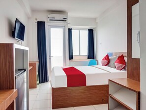 Une chambre d’hôtel avec un lit, une télévision, un bureau et une fenêtre avec des rideaux.