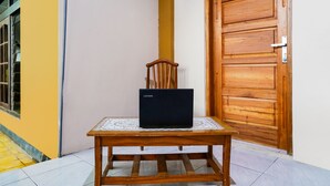 A wooden table with a laptop on it, positioned in front of a wooden door and a yellow wall. - OYO 91008 Tourismdesacibodasbabakangentong1syariah (Lembang)