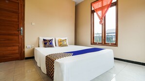 A hotel room with a large bed, two pillows, a blue throw, and a window with a red curtain. - OYO 91008 Tourismdesacibodasbabakangentong1syariah (Lembang)