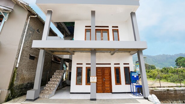 A two-story building with a white facade, a wooden door, and a staircase leading to the entrance. - OYO 91008 Tourismdesacibodasbabakangentong1syariah (Lembang)