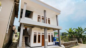 A two-story building with a flat roof, a staircase leading to the upper floor, and a signboard on the ground floor. - OYO 91008 Tourismdesacibodasbabakangentong1syariah (Lembang)
