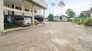 A multi-story building with a parking area, a dirt road, and surrounding greenery. - OYO 91008 Tourismdesacibodasbabakangentong1syariah (Lembang)