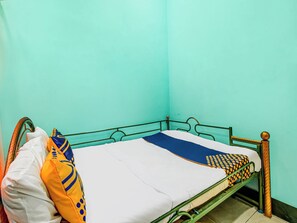 Un lit simple avec un cadre en métal, un matelas blanc et une couverture bleue.