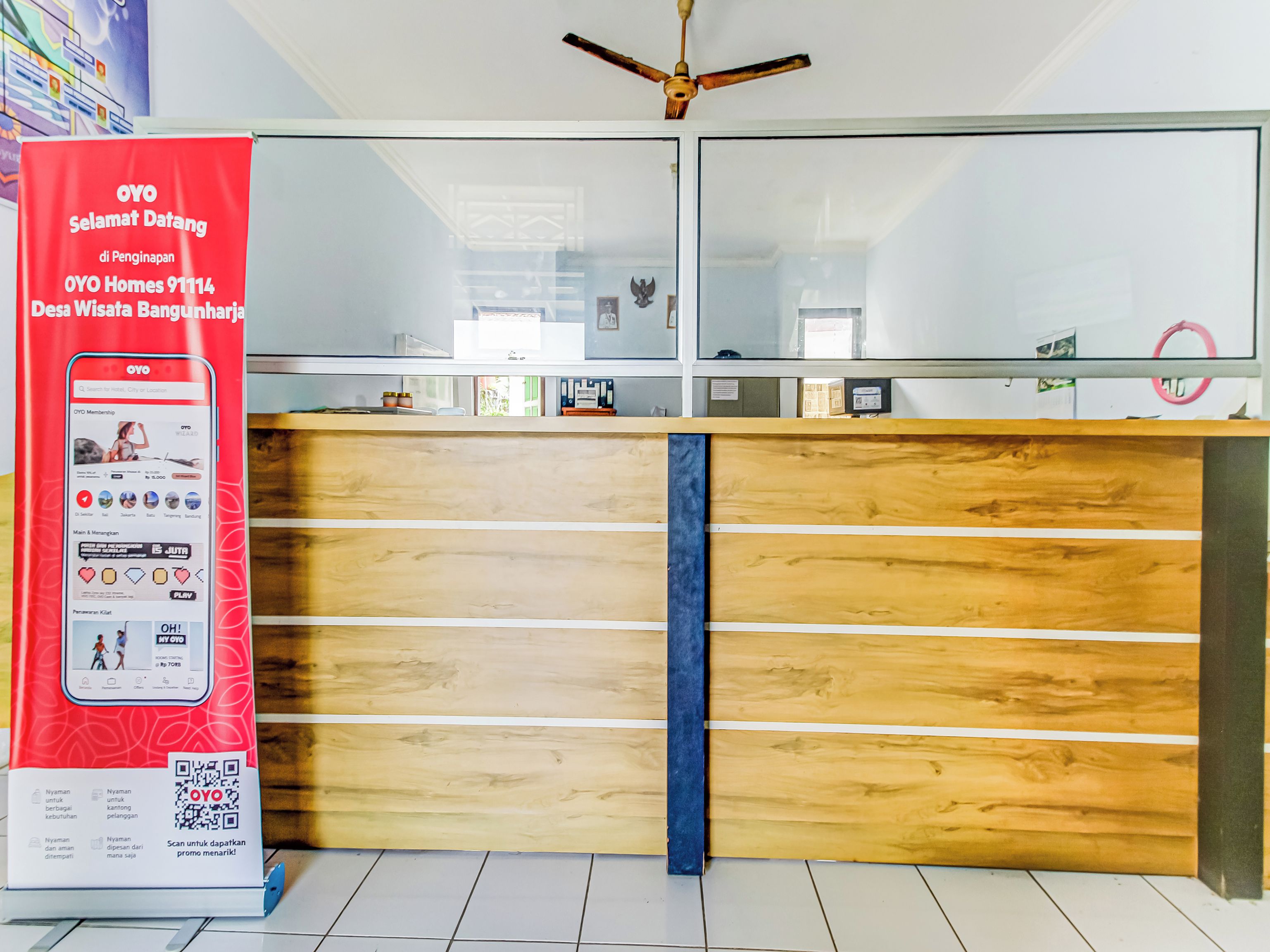 Un comptoir d’accueil avec un revêtement en bois et une touche de couleur bleue. Un présentoir rouge, utilisé à des fins promotionnelles, est visible sur la gauche et fait la publicité de l’adhésion à OYO, avec un code QR permettant d’obtenir de plus amples informations.