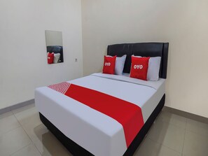 A hotel room with a bed, a headboard, a mirror, and a red and white bedspread. - Oke Guest House (Malang)