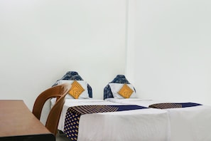 Ein Hotelzimmer mit zwei Betten, einem Holztisch und einem Stuhl.