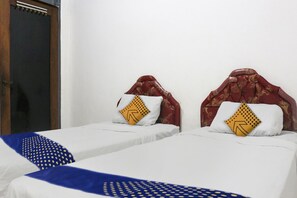 Una habitación de hotel con dos camas individuales, cada una con cabecera y almohada estampada con un diseño geométrico.