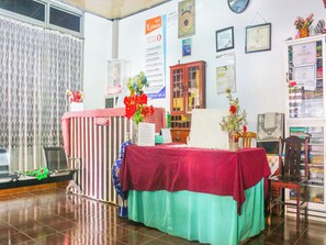 Un área de recepción con mostrador de check-in, una silla a rayas rojas y blancas, un armario de madera y varios certificados y avisos en la pared.