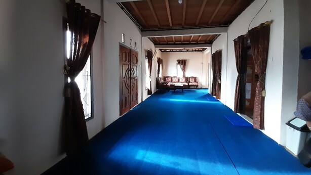 Un pasillo con alfombra azul, puertas de madera y un banco en el centro.
