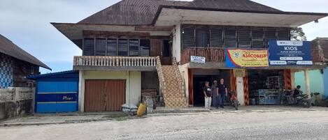 A two-story building with a sign for 'KIOS PURUK INDONESIA' and a blue container to the left.